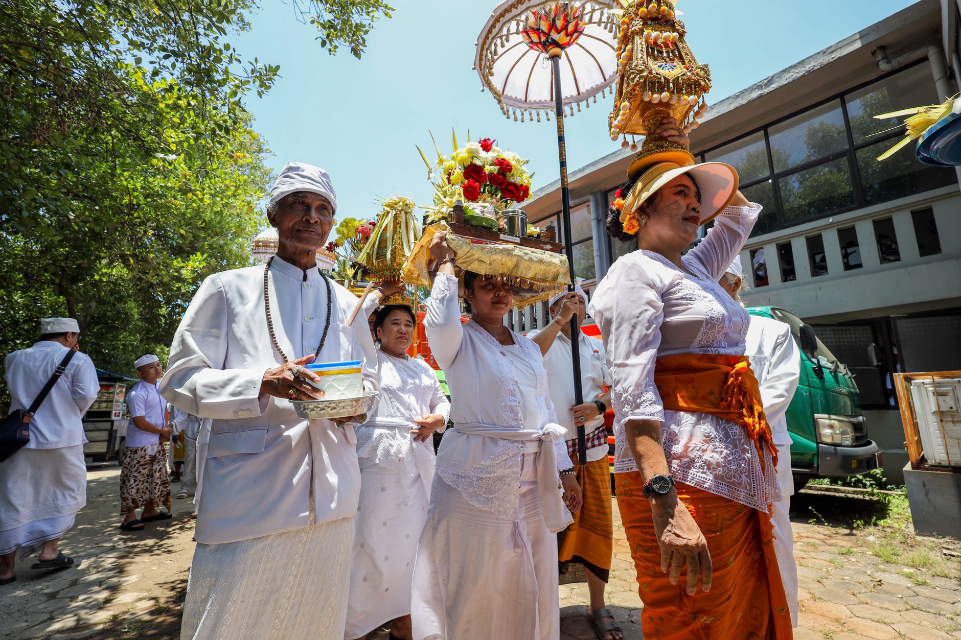 Masyarakat Bali berpakaian tradisional berpartisipasi dalam upacara Hindu yang meriah di luar ruangan.