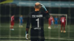 Seorang penjaga gawang sepak bola berdiri siap untuk melakukan tendangan penalti di lapangan.