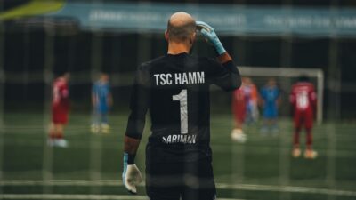 Seorang penjaga gawang sepak bola berdiri siap untuk melakukan tendangan penalti di lapangan.
