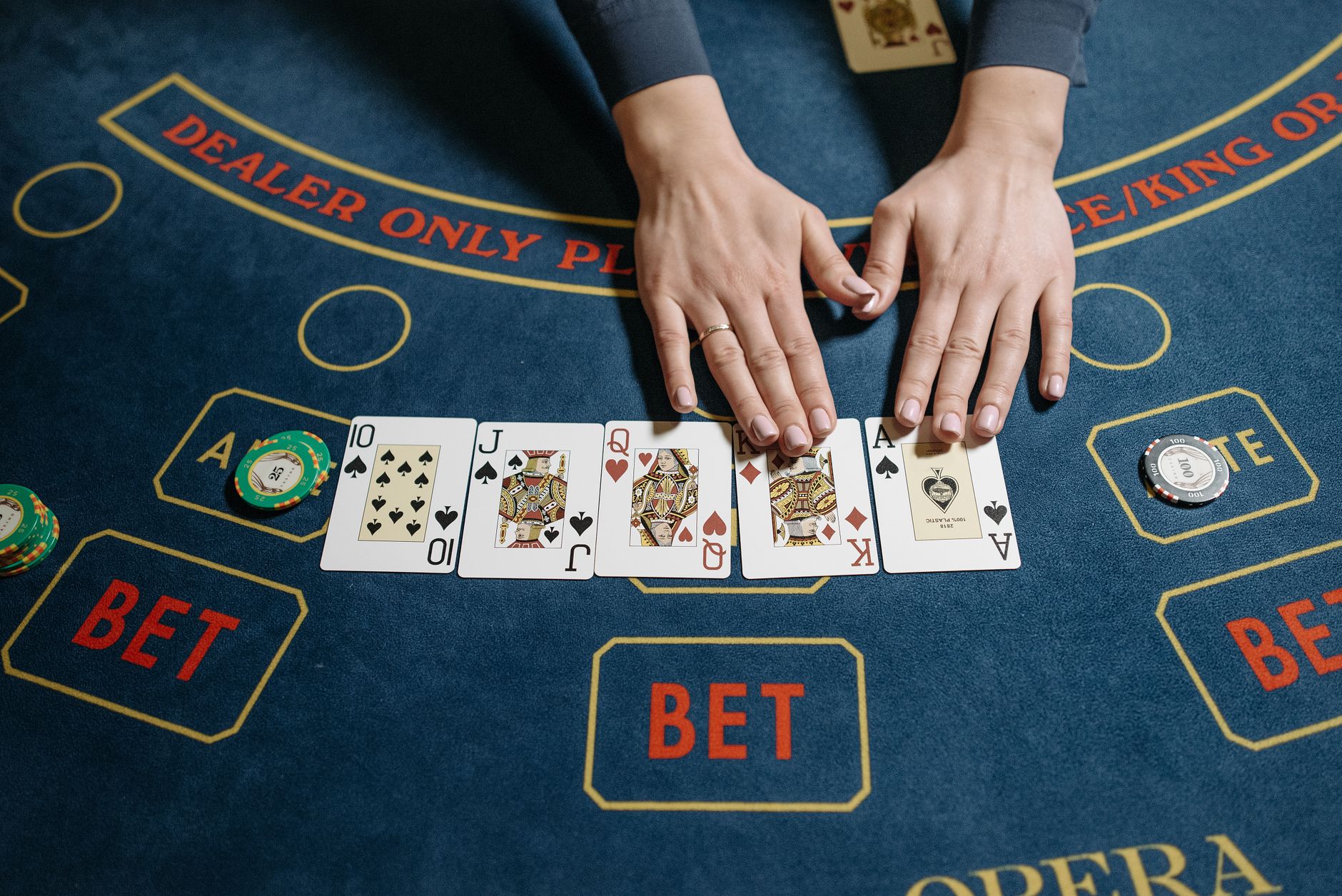 Pandangan atas permainan kasino dengan dealer yang menunjukkan tangan poker yang menang di meja felt.