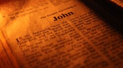Dekat fokus pada Injil Yohanes, menyoroti kitab-kitab suci di bawah cahaya hangat.