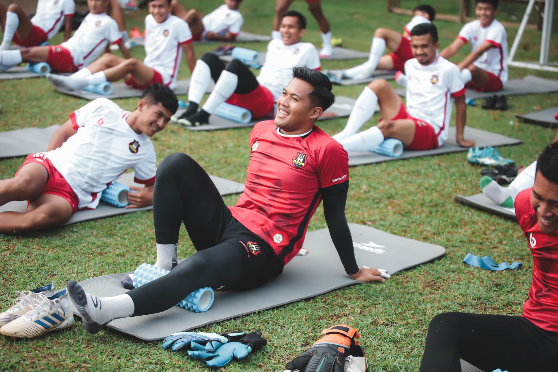 Pemain sepak bola yang melakukan latihan peregangan di lapangan berumput, Jakarta.