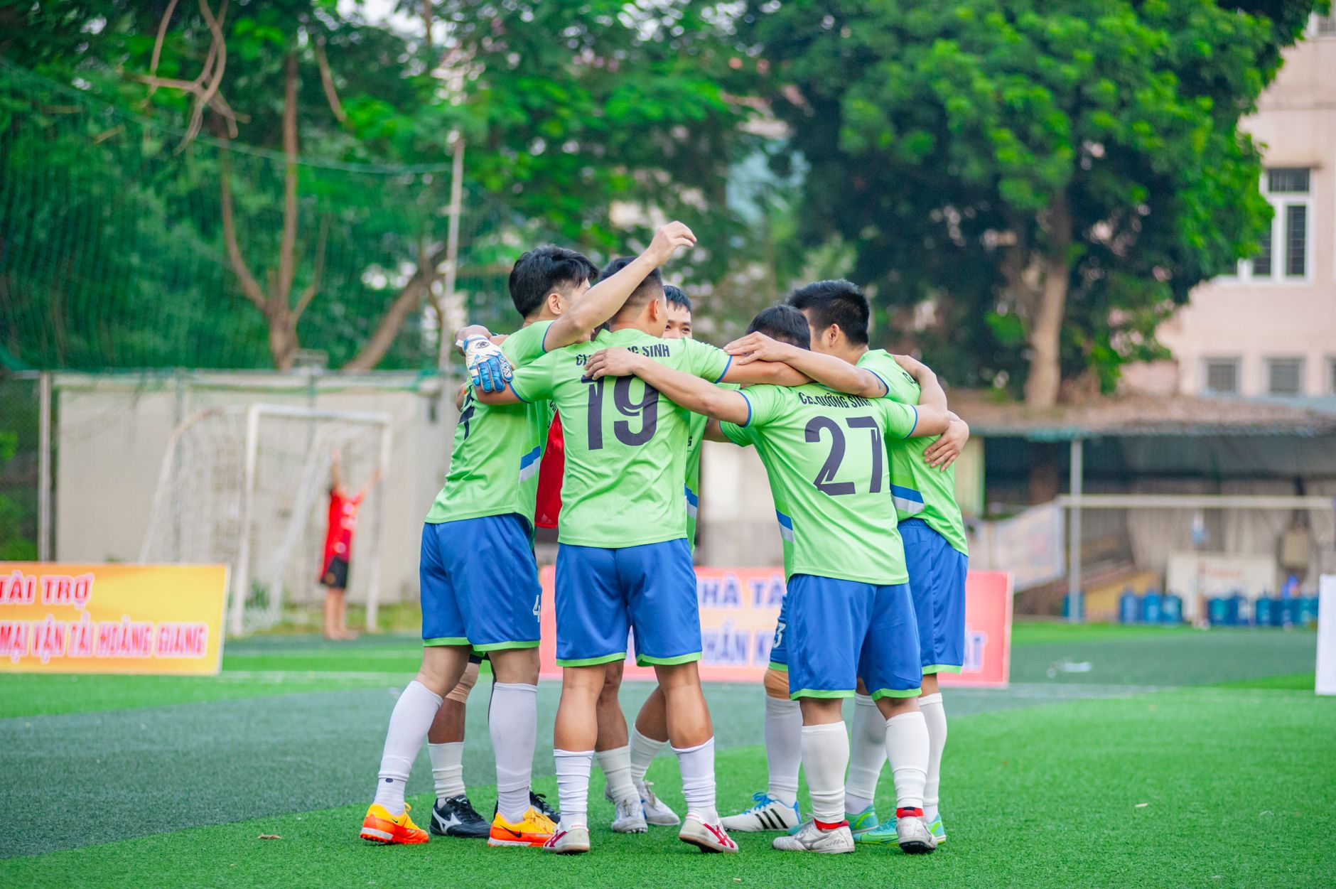 Sekelompok remaja laki-laki merayakan kemenangan bersama di lapangan terbuka.