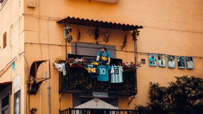 Balkon yang dihiasi dengan kaus sepak bola dan foto-foto pemain, menampilkan penghormatan kepada legenda sepak bola.