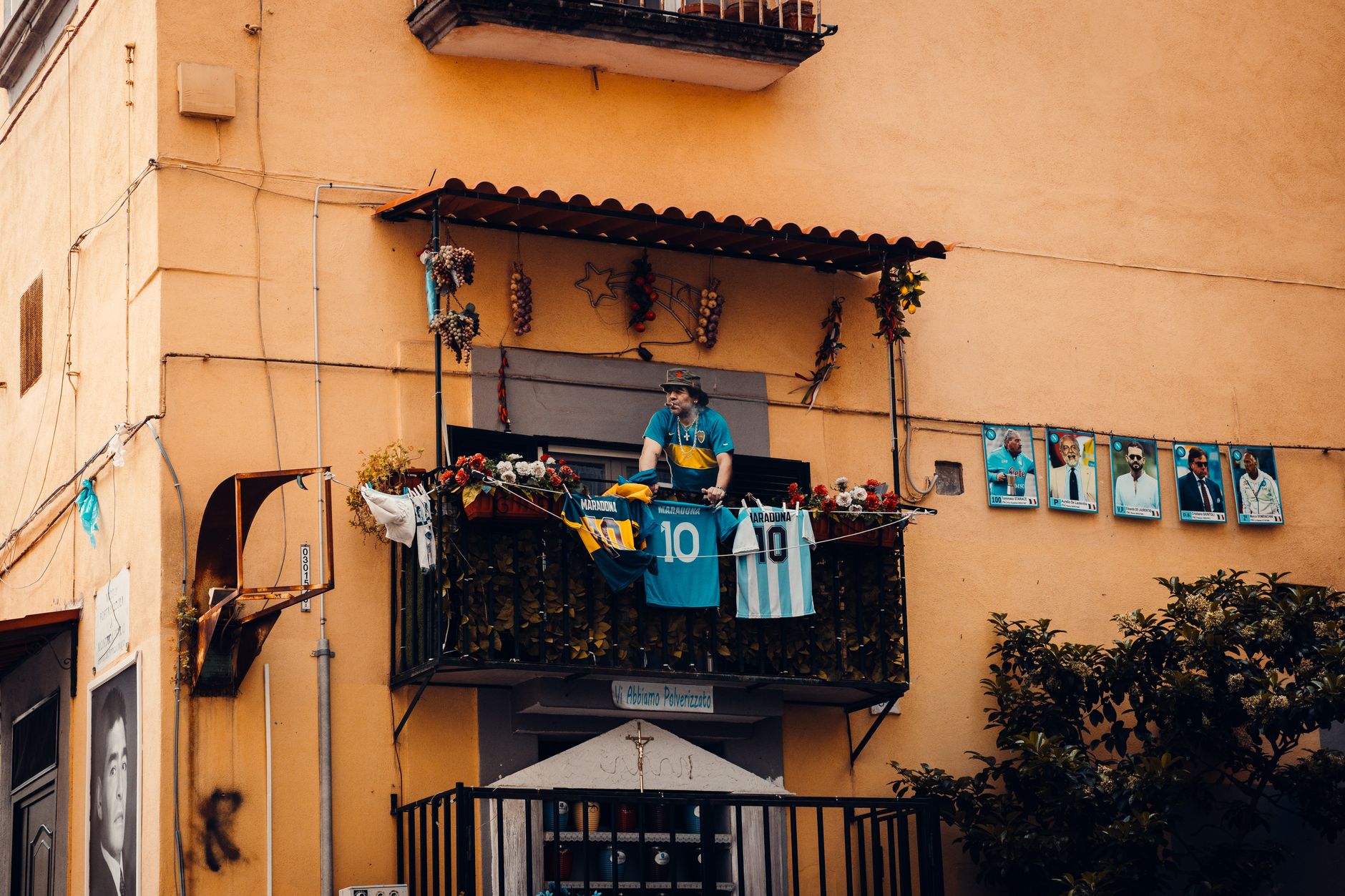 Balkon yang dihiasi dengan kaus sepak bola dan foto-foto pemain, menampilkan penghormatan kepada legenda sepak bola.