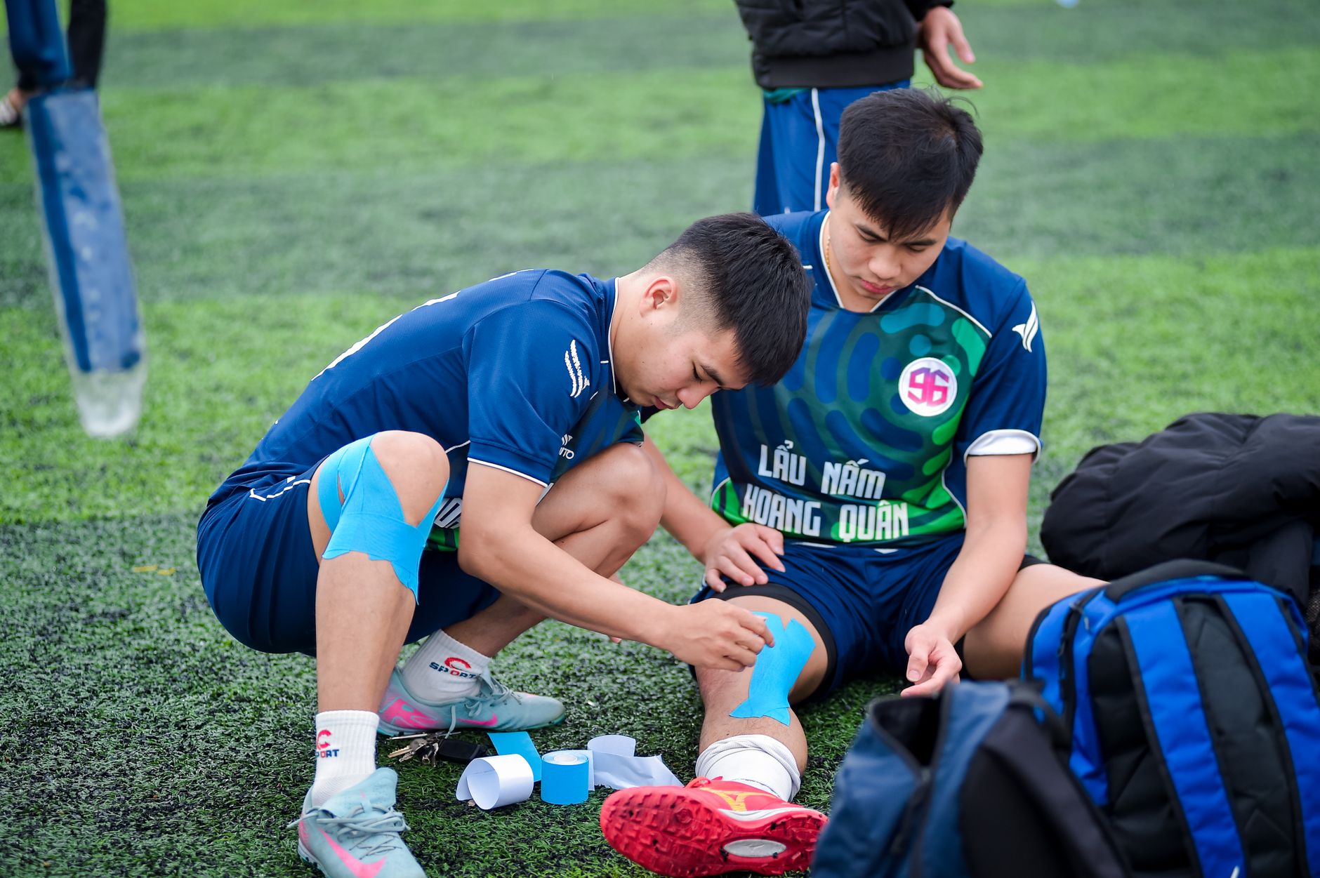 Pemain sepak bola mengaplikasikan pita kinesiologi di lapangan di Hà Nội, Vietnam.