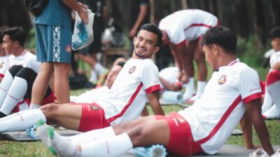 Pemain sepak bola di Jakarta bersantai di atas tikar selama sesi latihan di luar ruangan.