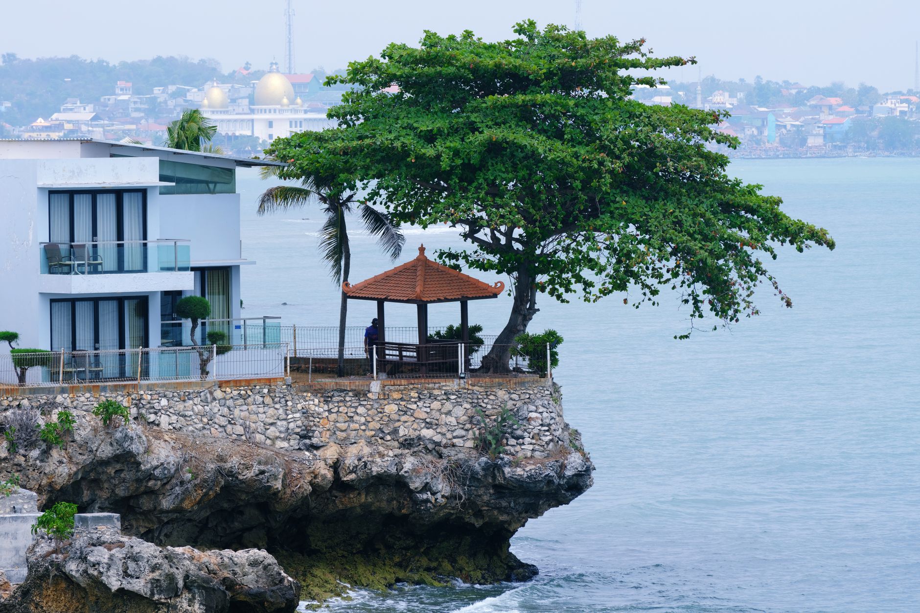 Pemandangan indah sebuah rumah dan gazebo di tebing yang menghadap ke laut, memberikan pelarian yang damai.