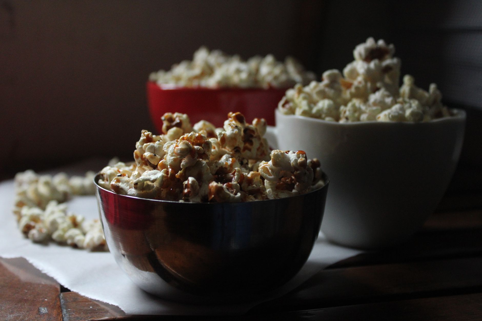 Pemandangan nyaman dengan popcorn dalam mangkuk di atas meja kayu, sempurna untuk suasana malam menonton film.