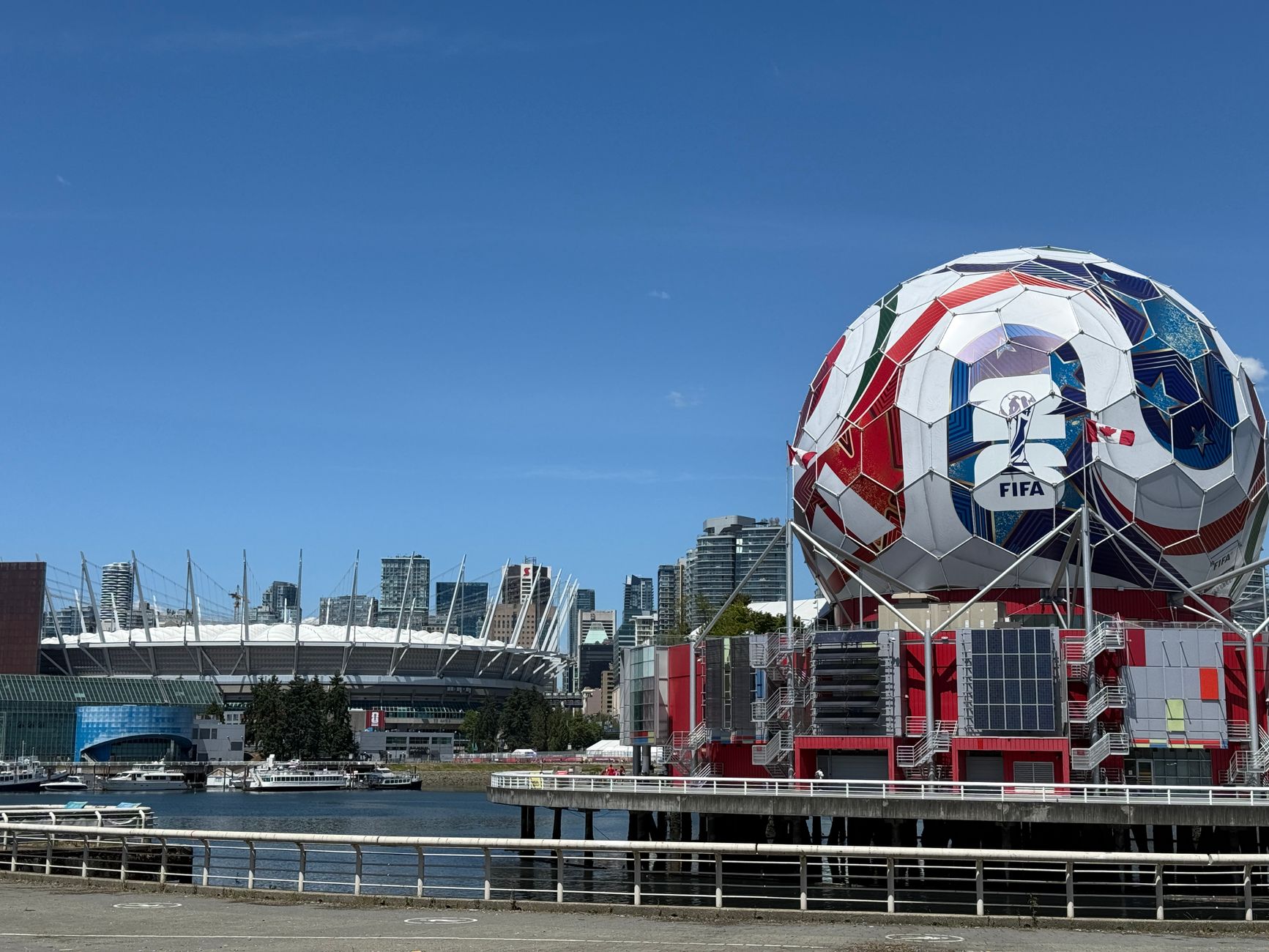 Bola sepak FIFA yang ikonik dan stadion Vancouver, menampilkan arsitektur olahraga perkotaan.