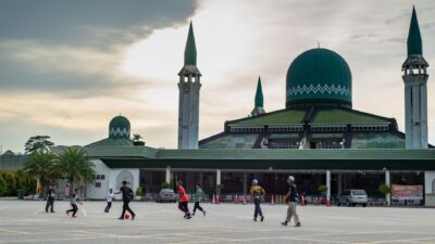 Sorotan: 3 Fakta setelah Timnas Indonesia dan Malaysia Bermain Imbang di FIFA ASEAN Cup 2026 8 Anak-anak bermain sepak bola di depan masjid dengan kubah hijau dan menara, di bawah langit yang mendung.