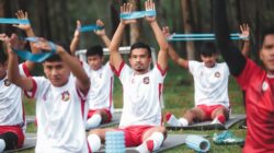 Sekelompok pemain sepak bola muda berlatih dengan band resistensi selama latihan di luar ruangan.