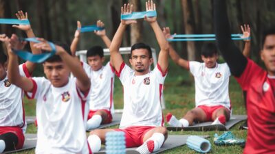 Sekelompok pemain sepak bola muda berlatih dengan band resistensi selama latihan di luar ruangan.
