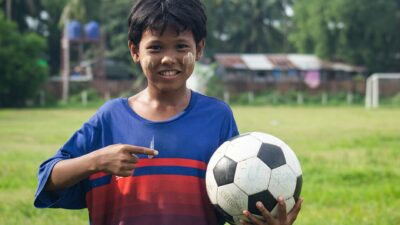 Bocah tersenyum dengan thanaka di wajahnya memegang bola sepak di Myawaddy, Myanmar.