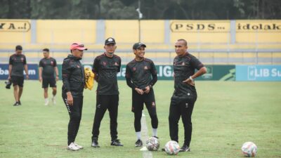 Sorotan: Maarten Paes Ingatkan Timnas Indonesia: Jangan Anggap Remeh Lawan di FIFA ASEAN Cup 2026 8 Sekelompok pelatih Indonesia berdiskusi di lapangan sepak bola di siang hari.