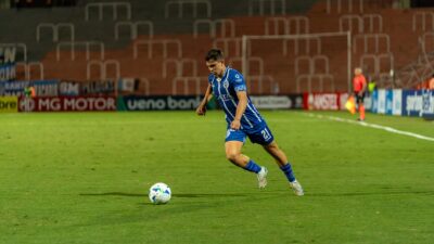 Sorotan: Persib Libur 4 Hari, Igor Tolic Ingatkan Tantangan Besar di Oktober: 10 Pertandingan Berun... 7 Seorang pemain sepak bola dengan jersey biru menggiring bola di lapangan yang terang benderang saat pertandingan malam.