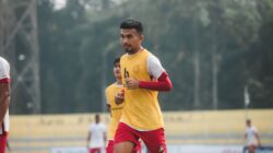Sorotan: Starting XI Timnas Indonesia Vs Malaysia: John Herdman Cadangkan Mitchell Baker 2 Pengambilan gambar dinamis seorang pemain sepak bola di tengah permainan di lapangan terbuka, menunjukkan tekad dan fokus.