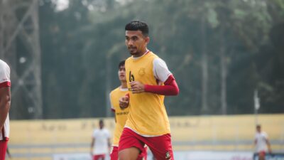 Sorotan: Starting XI Timnas Indonesia Vs Malaysia: John Herdman Cadangkan Mitchell Baker 8 Pengambilan gambar dinamis seorang pemain sepak bola di tengah permainan di lapangan terbuka, menunjukkan tekad dan fokus.