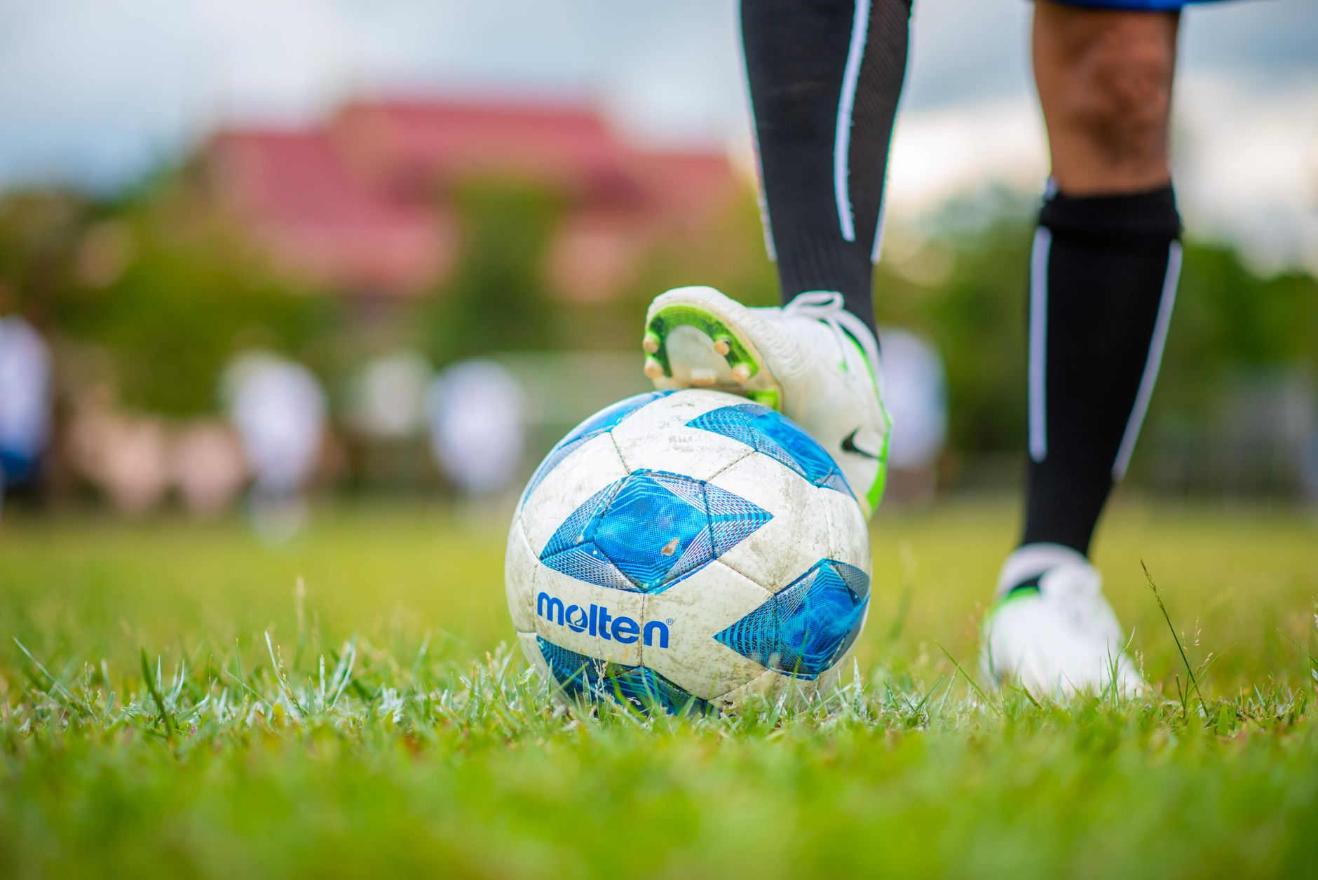 Sebuah bidikan mendetail dari kaki pemain di bola sepak selama pertandingan, menekankan olahraga dan gerakan.