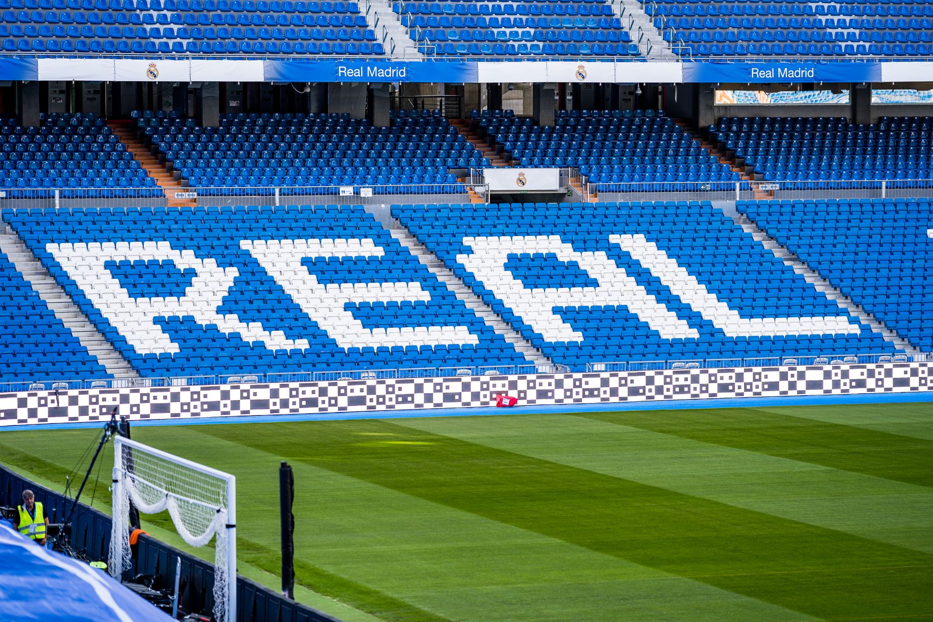 Area tempat duduk kosong di stadion Real Madrid dengan 'REAL' ditampilkan dengan jelas dalam warna putih.