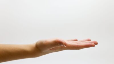 Close-up rinci dari tangan manusia yang terbuka di latar belakang putih, menekankan gerakan dan ekspresi.