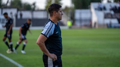 Pelatih sepak bola mengamati strategi pertandingan selama pertandingan luar ruangan.