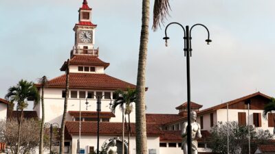 Pemandangan eksterior Perpustakaan Balme di Universitas Ghana dengan pohon palem dan langit yang cerah.
