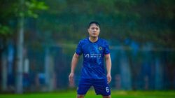 Foto dinamis seorang pemain sepak bola yang sedang beraksi di lapangan hujan di Hanoi, Vietnam.