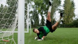 Kiper sepak bola melakukan penyelamatan dramatis di udara selama pertandingan.