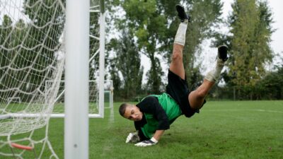 Kiper sepak bola melakukan penyelamatan dramatis di udara selama pertandingan.