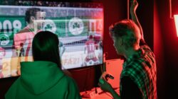 Catatan Sepak Bola: Tonton Live Streaming FIFA ASEAN Cup 2026 di Vidio: Timnas Indonesia Vs Bangladesh 4 Dua teman yang menikmati sesi permainan video yang menegangkan di dalam ruangan, diabadikan dengan pencahayaan yang cerah.