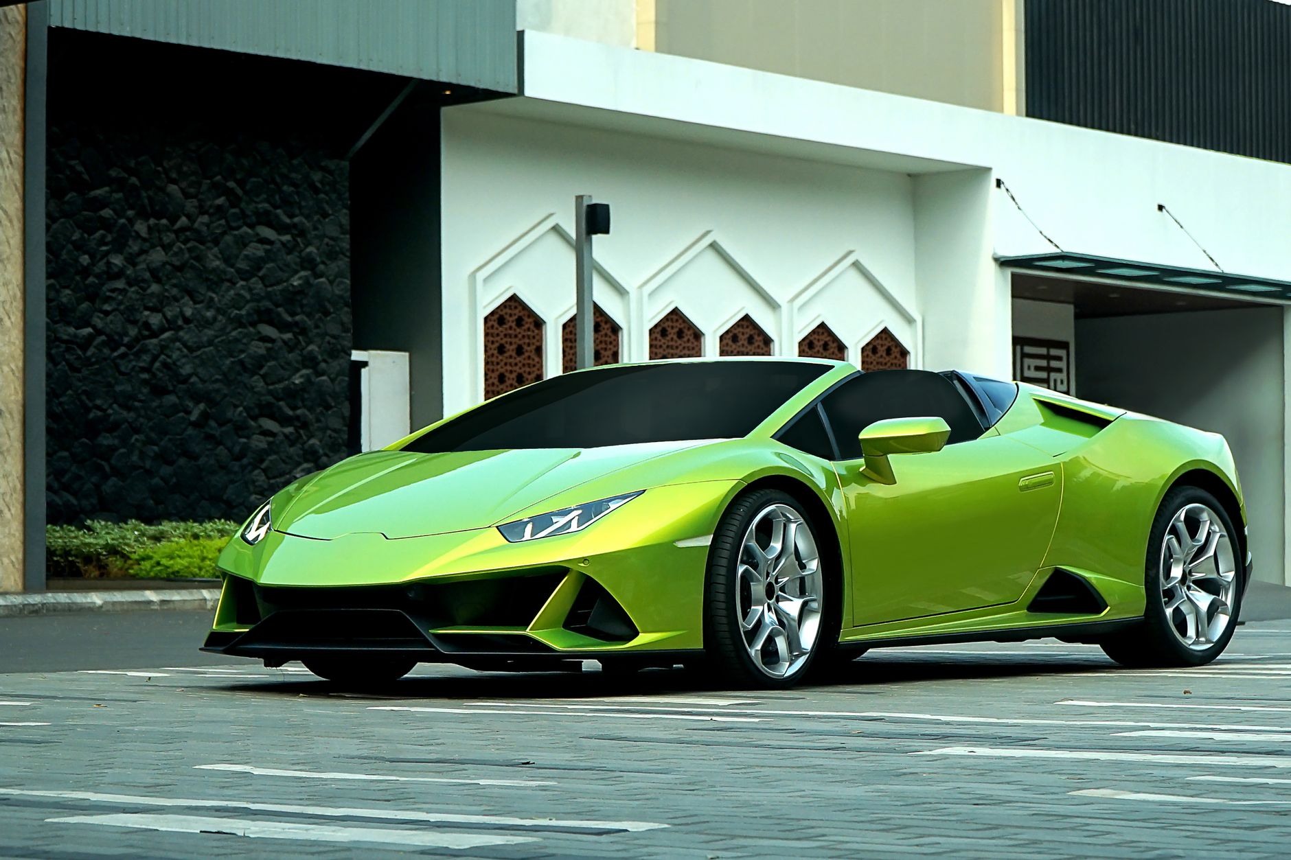 Sebuah Lamborghini hijau mencolok diparkir di lingkungan perkotaan modern di Jakarta, Indonesia.