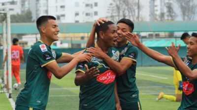 Pemain sepak bola merayakan gol di lapangan dengan semangat dan kerja sama tim.