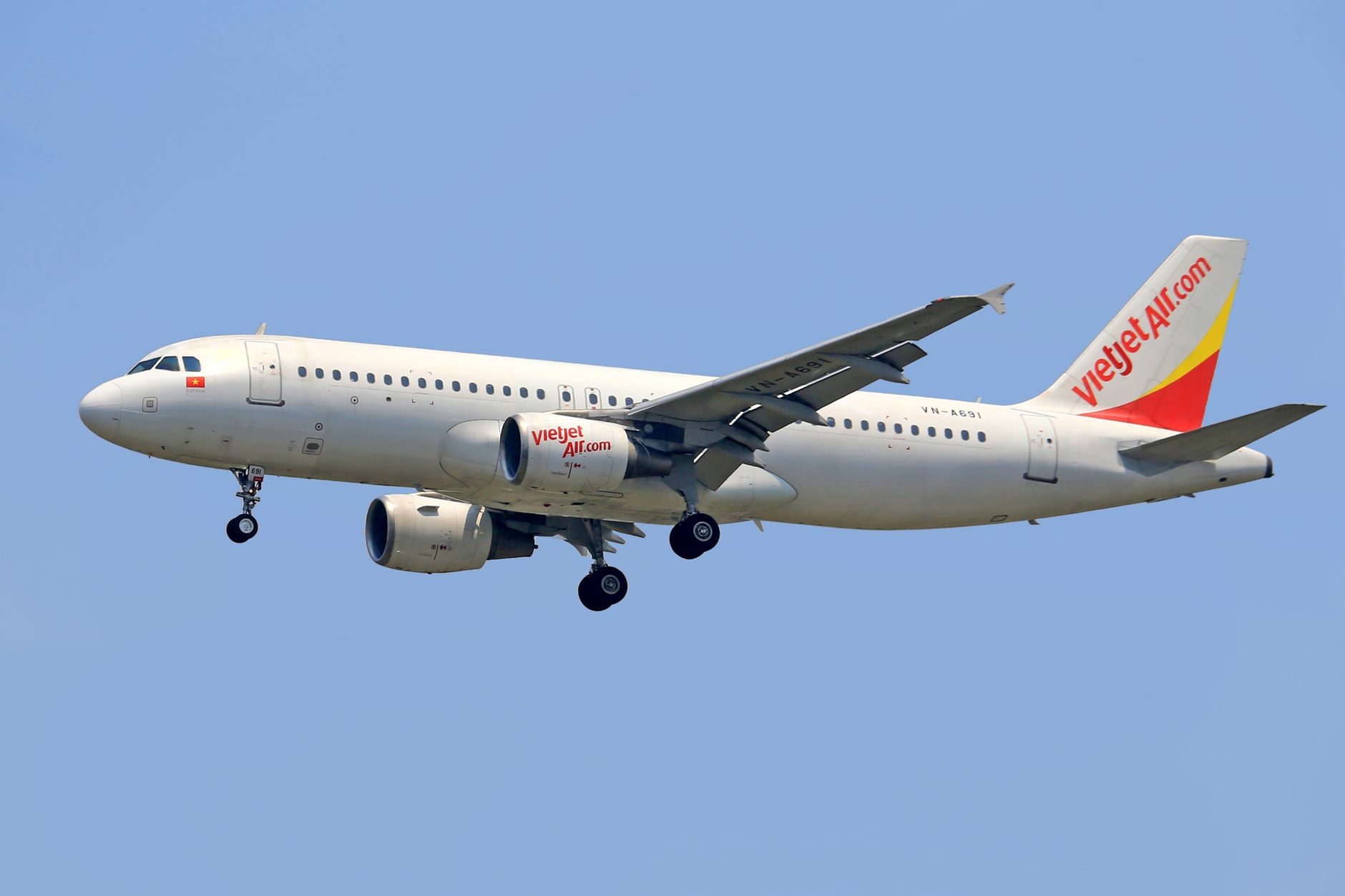 Sebuah Airbus Vietjet Air yang terbang, menampilkan teknologi penerbangan di bawah langit biru cerah.