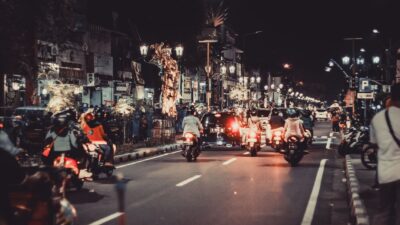 Jalan malam yang meriah dengan mobil dan sepeda motor. Kehidupan perkotaan dan cahaya cerah menangkap esensi energi pusat kota.