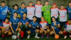 Sekelompok pemain sepak bola amatir berpose di lapangan dengan berbagai kaus tim.