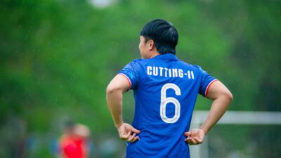 Seorang pemain sepak bola berdiri di lapangan di Hà Nội, Việt Nam, selama pertandingan yang diguyur hujan.