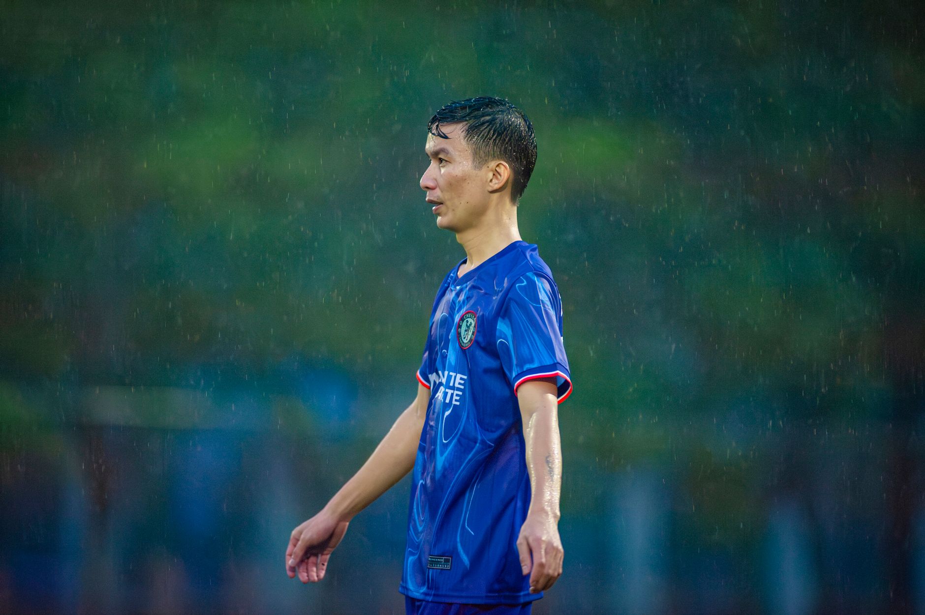 Seorang pemain sepak bola tertangkap kamera sedang beraksi selama pertandingan yang diguyur hujan di Hà Nội, Vietnam.