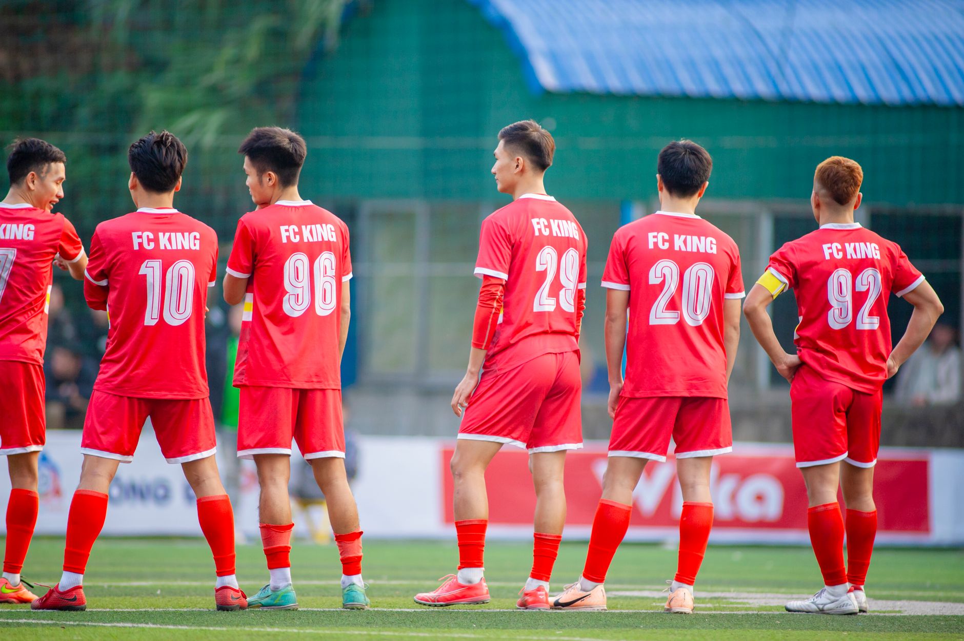 Pemain sepak bola berseragam merah dari FC King berdiri di lapangan di Hà Nội, Vietnam.