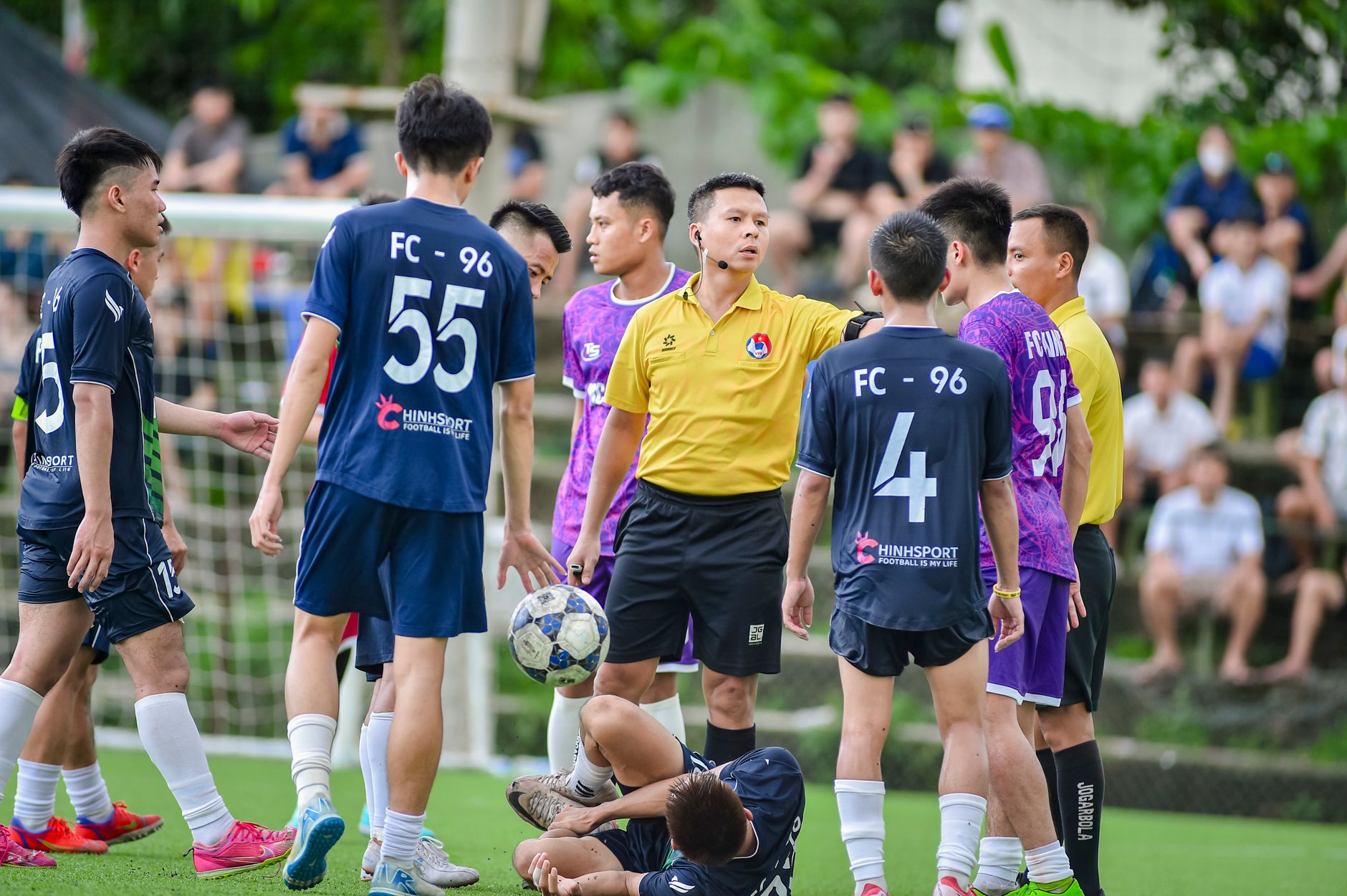 Adegan dinamis pertandingan sepak bola remaja dengan wasit di Hà Nội.