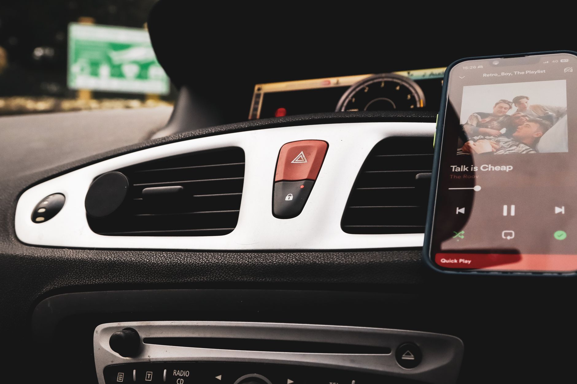 Interior mobil dengan smartphone di Spotify dan kontrol dashboard yang fokus.