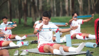 Sekelompok pemain sepak bola muda berlatih dengan band resistensi di luar ruangan di Jakarta, Indonesia.