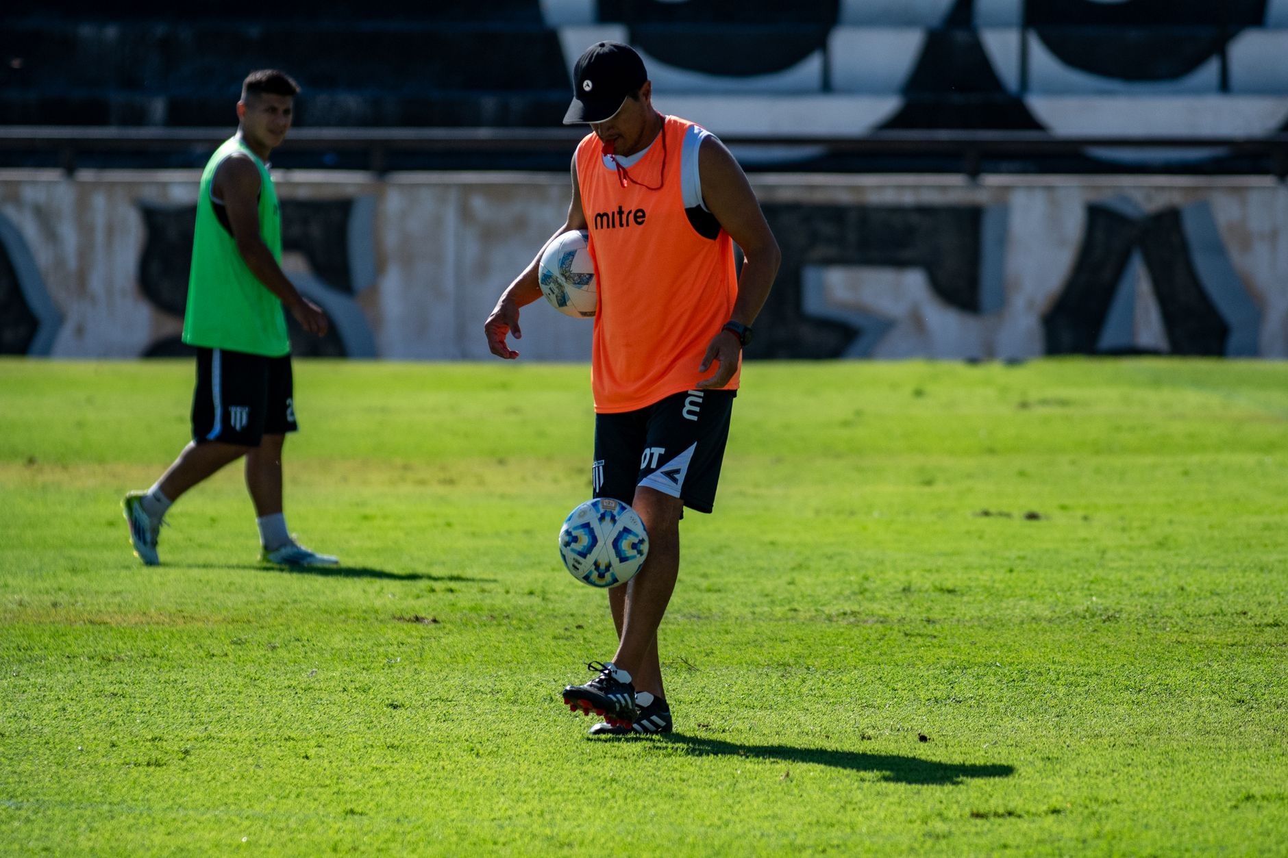 Dua pemain sepak bola berlatih dengan bola selama sesi latihan cerah di lapangan rumput.