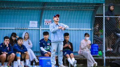 Para pemain sepak bola dan pelatih berada di pinggir lapangan olahraga di Hà Nội, Việt Nam.