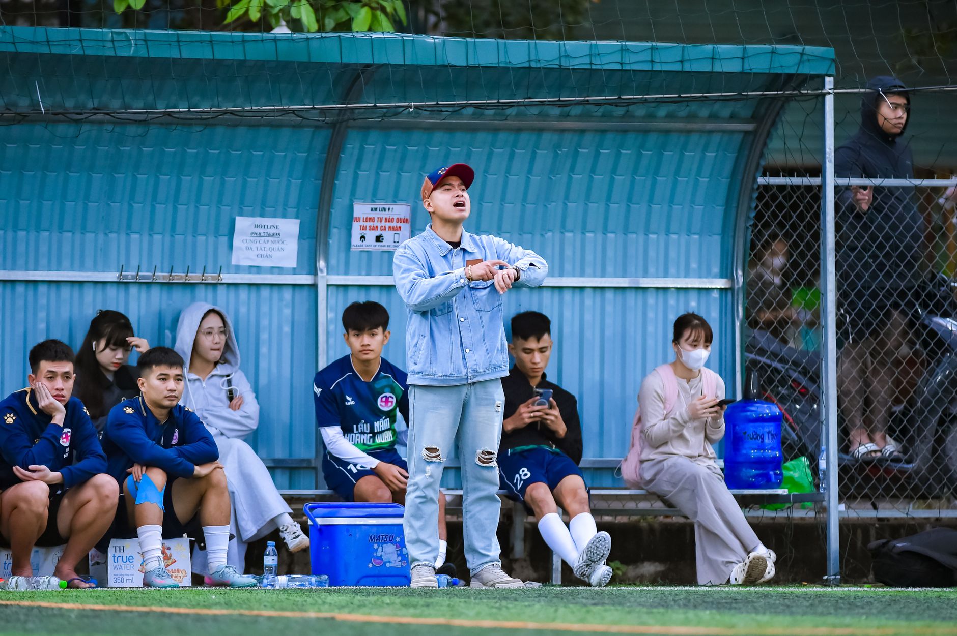 Para pemain sepak bola dan pelatih berada di pinggir lapangan olahraga di Hà Nội, Việt Nam.