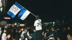 Update: Pelaku Pembunuhan Bobotoh Persib Ditangkap, Umuh Muchtar Apresiasi Polresta Bogor 1 Sebuah kumpulan jalanan yang meriah di malam hari dengan bendera yang ditampilkan secara mencolok di tengah kerumunan besar.